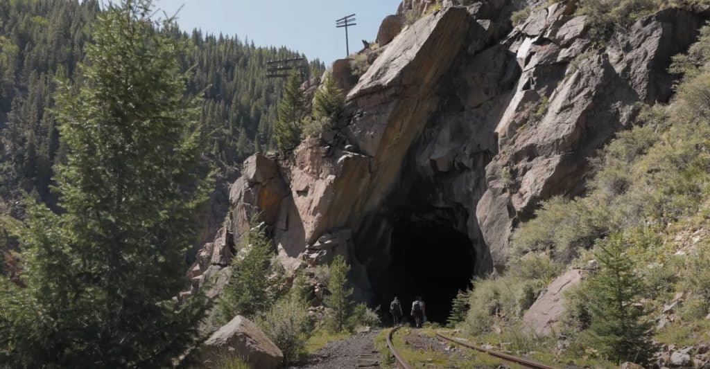 Man-Standing-At-Cave-Entrance